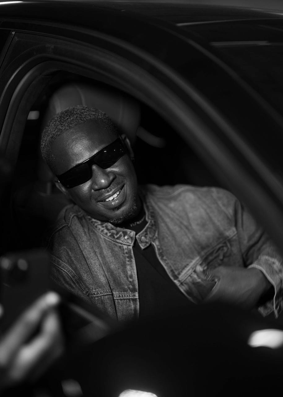Lenko Psycho smiling from the driver's seat, black and white